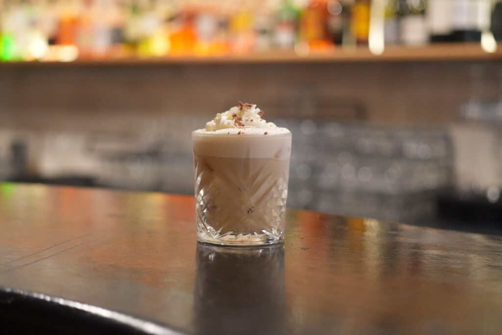 Frothy coffee cocktail on bar in crystal glass